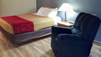 A hotel room with a bed, a chair, a nightstand, and a lamp.