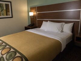 Una habitación de hotel con cama, mesita de noche, lámpara y un cuadro en la pared.