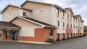 Un hotel de varios pisos con techo plano, numerosas ventanas y un estacionamiento al frente.