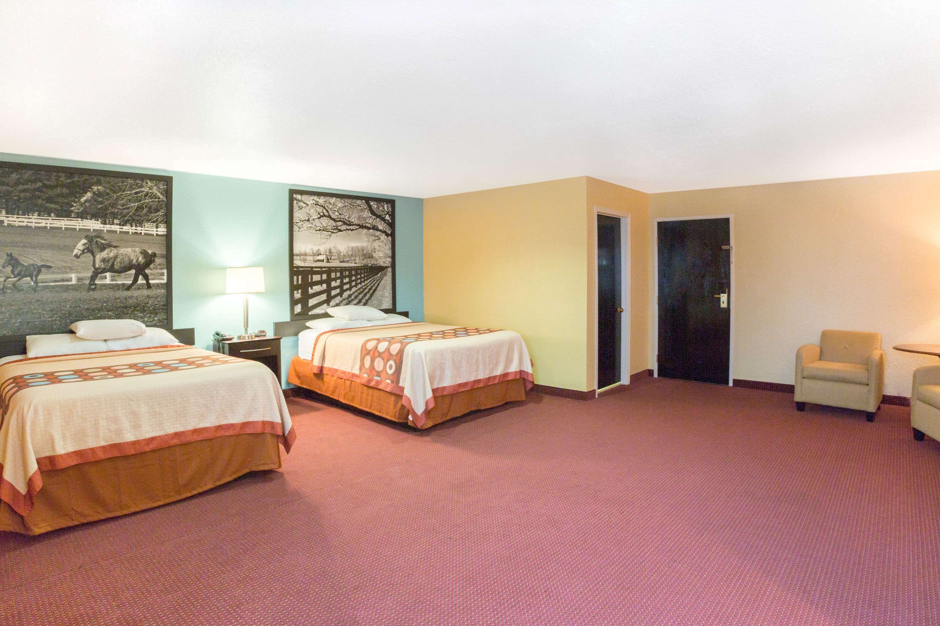 Habitación de hotel con dos camas, un escritorio, una silla y una puerta.