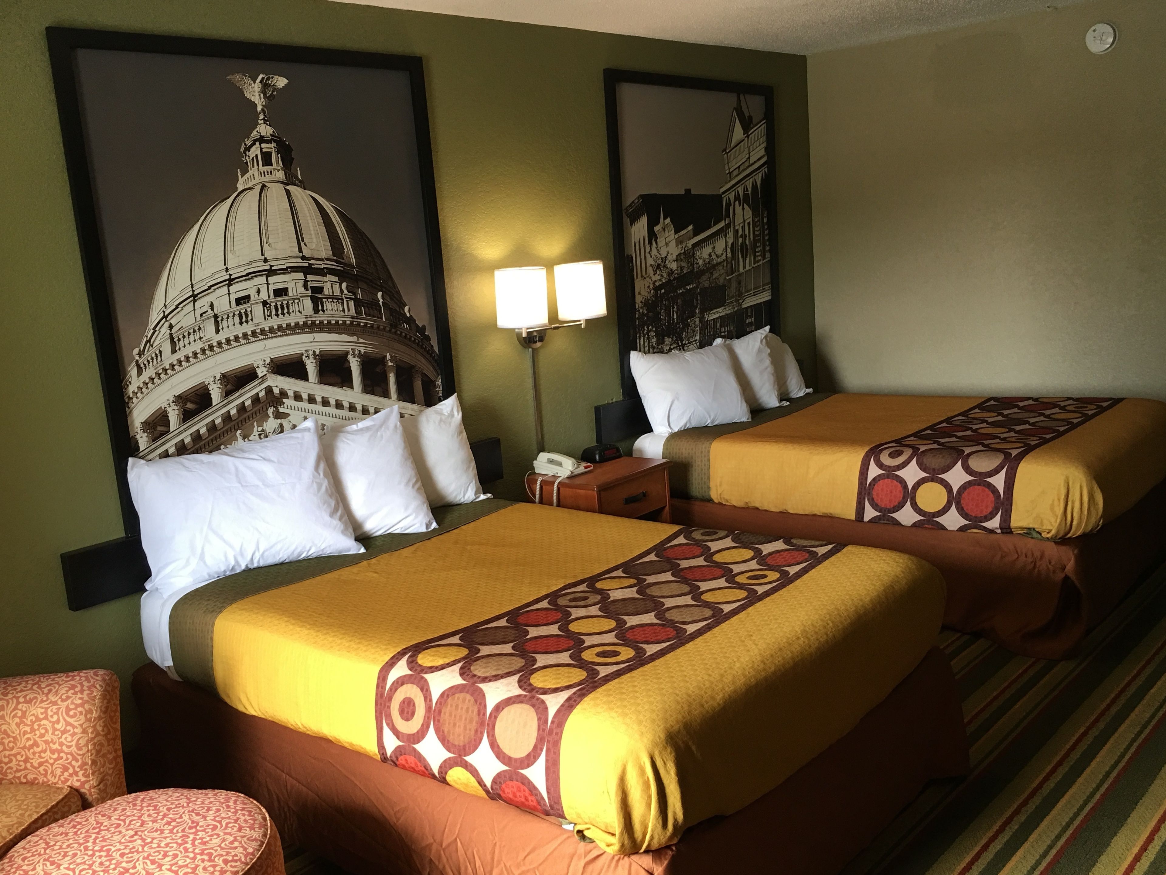 Une chambre d’hôtel avec deux lits, une table de chevet, une lampe et une chaise.