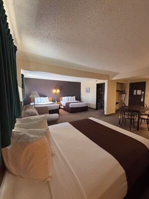 A hotel room with two beds, a dining table, and chairs.