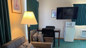 Une chambre d’hôtel équipée d’un canapé, d’une table, d’une télévision et d’un réfrigérateur.