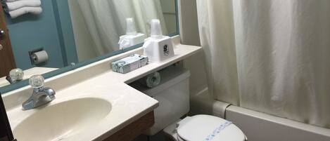A bathroom with a sink, toilet, and shower curtain.