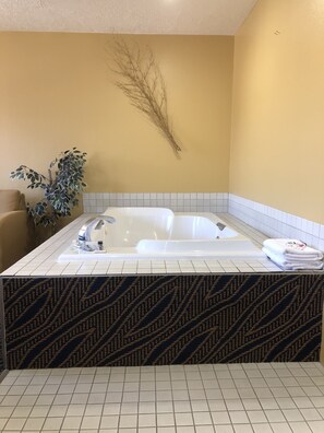 A bathroom with a large bathtub, a potted plant, and a tiled floor. - Super 8 by Wyndham Cedar City (Cedar City)