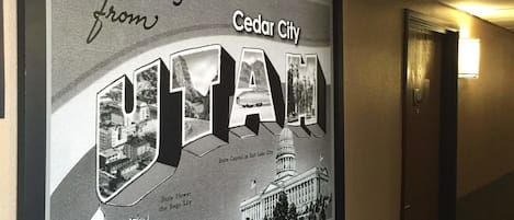 A corridor with a framed welcome sign for Cedar City, Utah, featuring a state capitol building and the state flower, the Sequoia Lily.