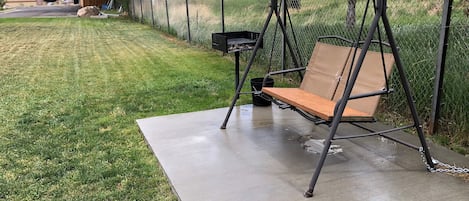 A swing set with a bench, a metal frame, and a chain.