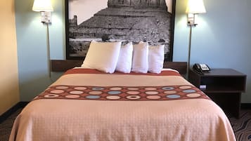 A hotel room with a large bed, two bedside lamps, a nightstand with a phone, and a large framed picture on the wall.
