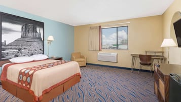Habitación de hotel con cama, dos sillas, escritorio, televisor y ventana con vistas.