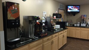 A coffee station with a coffee machine, a clock, and a TV displaying a news program.