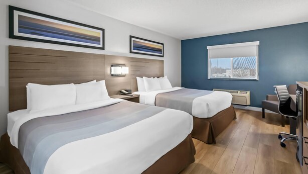 A hotel room with two beds, a desk, a chair, a lamp, and two framed pictures on the wall. - Quality Inn Neosho (Neosho)