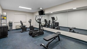 A gym with exercise equipment, a bench, a water dispenser, and a mirror on the wall. - Quality Inn Neosho (Neosho)