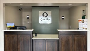 A reception desk with a 'Quality by Choice Hotels' sign, a computer monitor, and a QR code on the wall. - Quality Inn Neosho (Neosho)