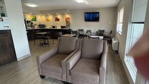 A modern interior with a sofa, dining area, kitchen, and a TV mounted on the wall. - Quality Inn Neosho (Neosho)