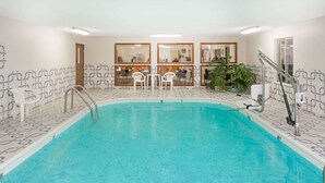 An indoor swimming pool with clear water, surrounded by patterned walls and a seating area with chairs. - Super 8 by Wyndham Pekin/Peoria Area (Pekin)