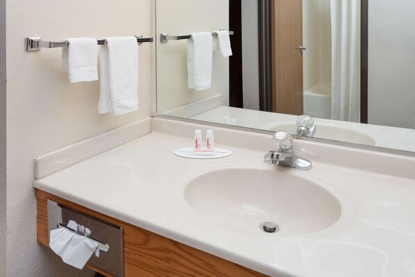 A bathroom with a white sink, a mirror, and a towel rack.