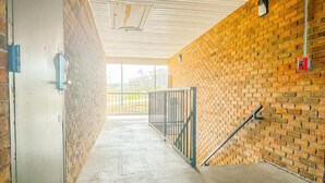 A covered hallway with brick walls and a concrete floor, leading to a gated area. - Regal Inn Guntersville Hwy 431 (Guntersville)