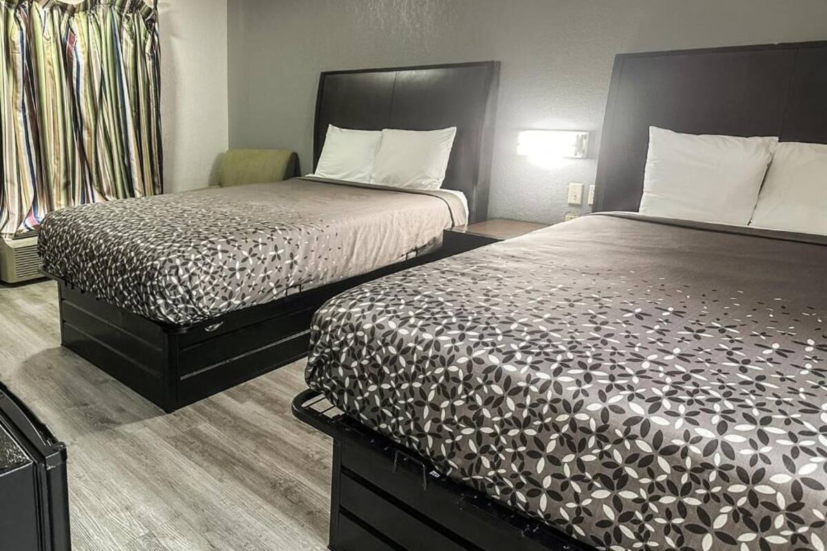 A hotel room with two beds, a wardrobe, and a mirror.
