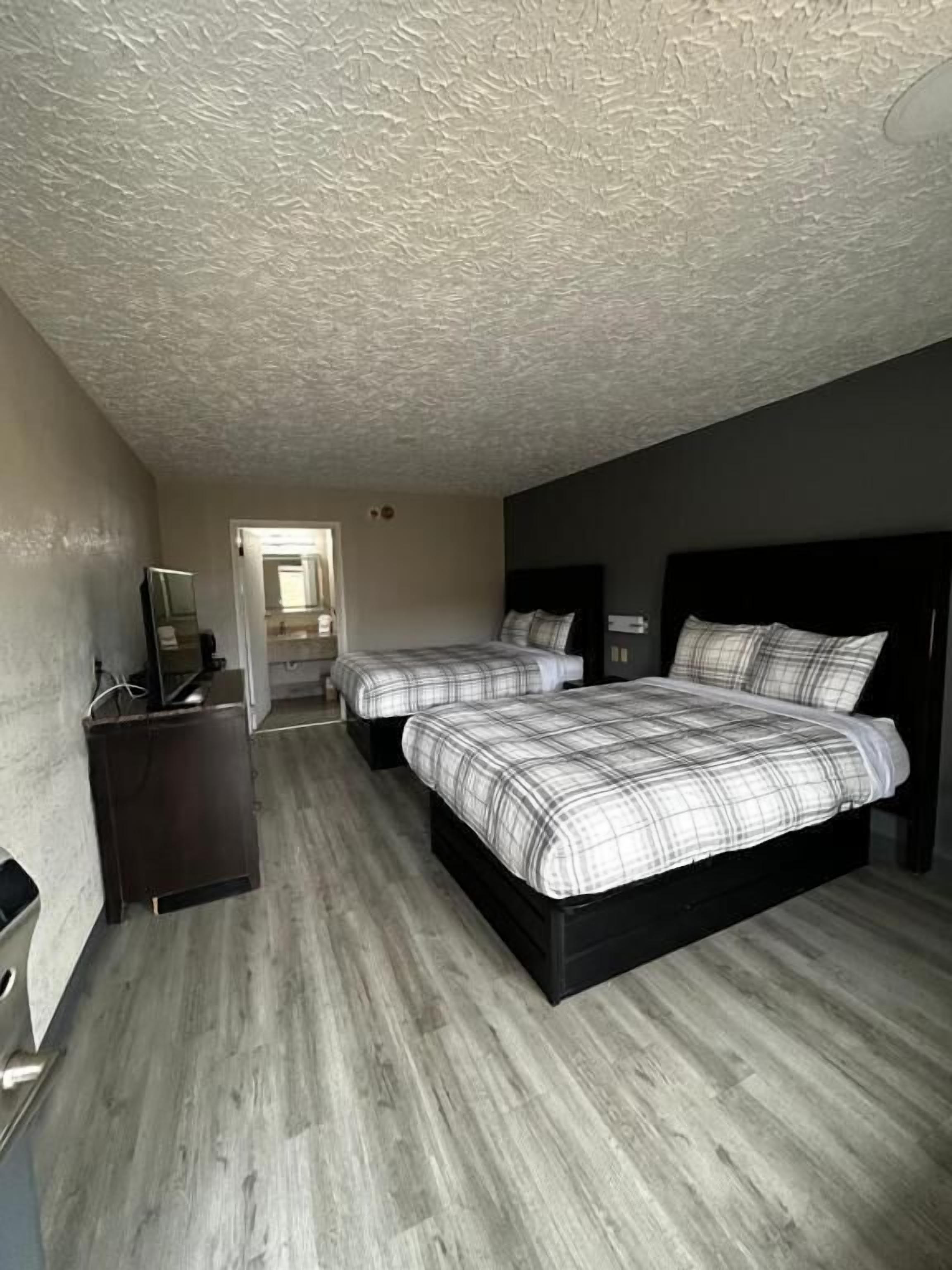 Una habitación con dos camas, un escritorio y un espejo.