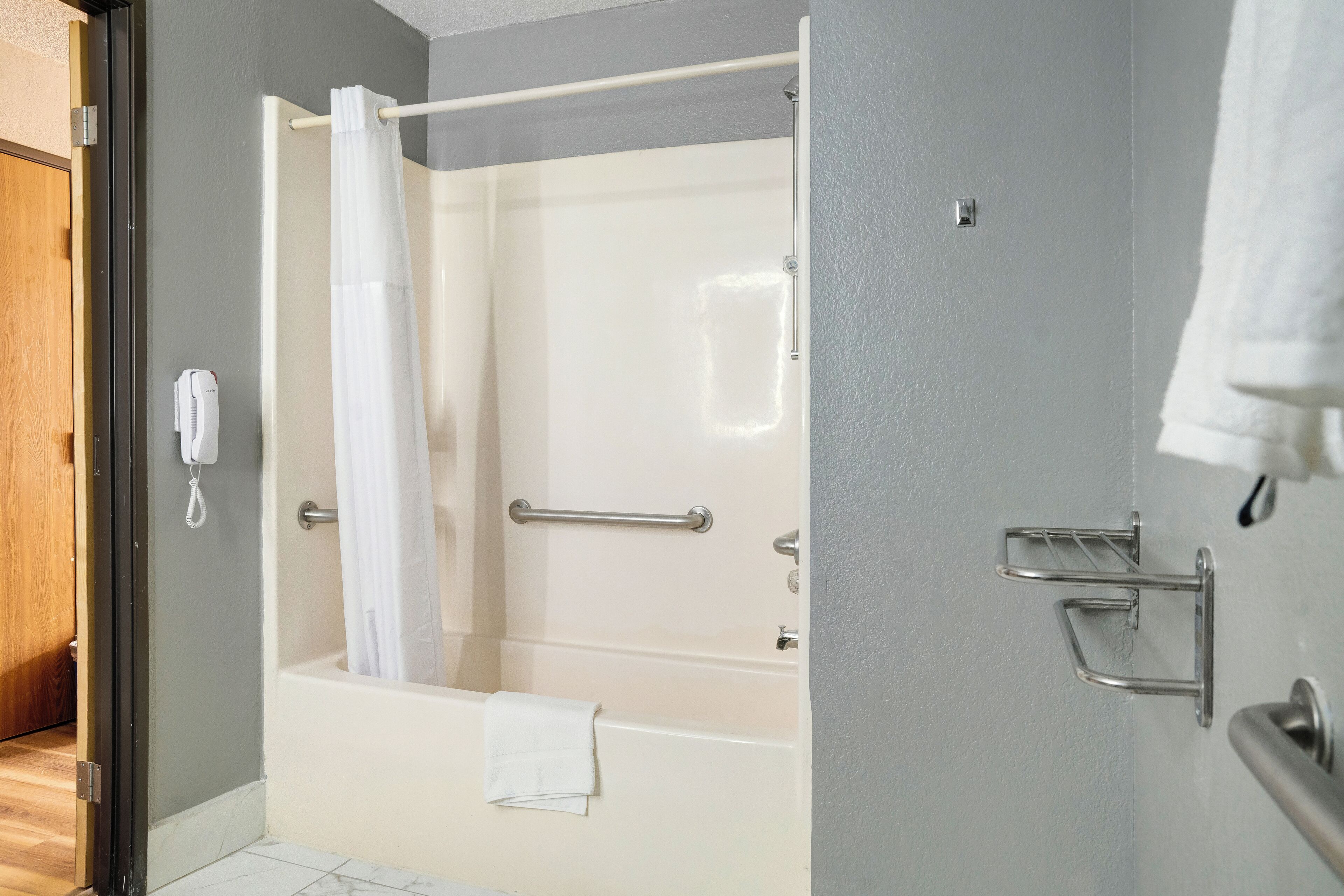 Ein modernes Badezimmer mit einer Badewanne, einer Duschvorhang, einem Handtuchhalter und einem Händetrockner.