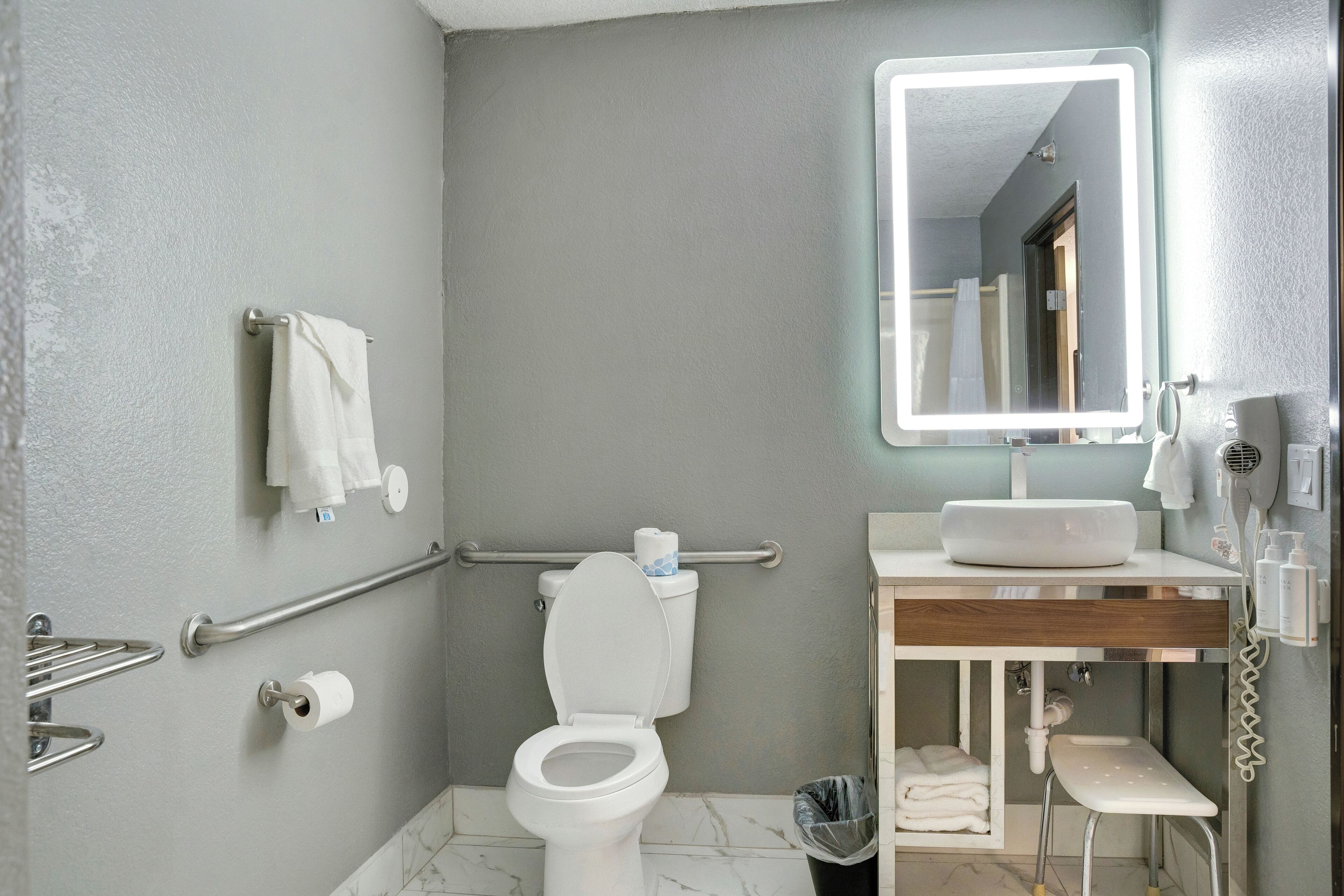 Une salle de bain moderne équipée de toilettes, d’un lavabo et d’un miroir.
