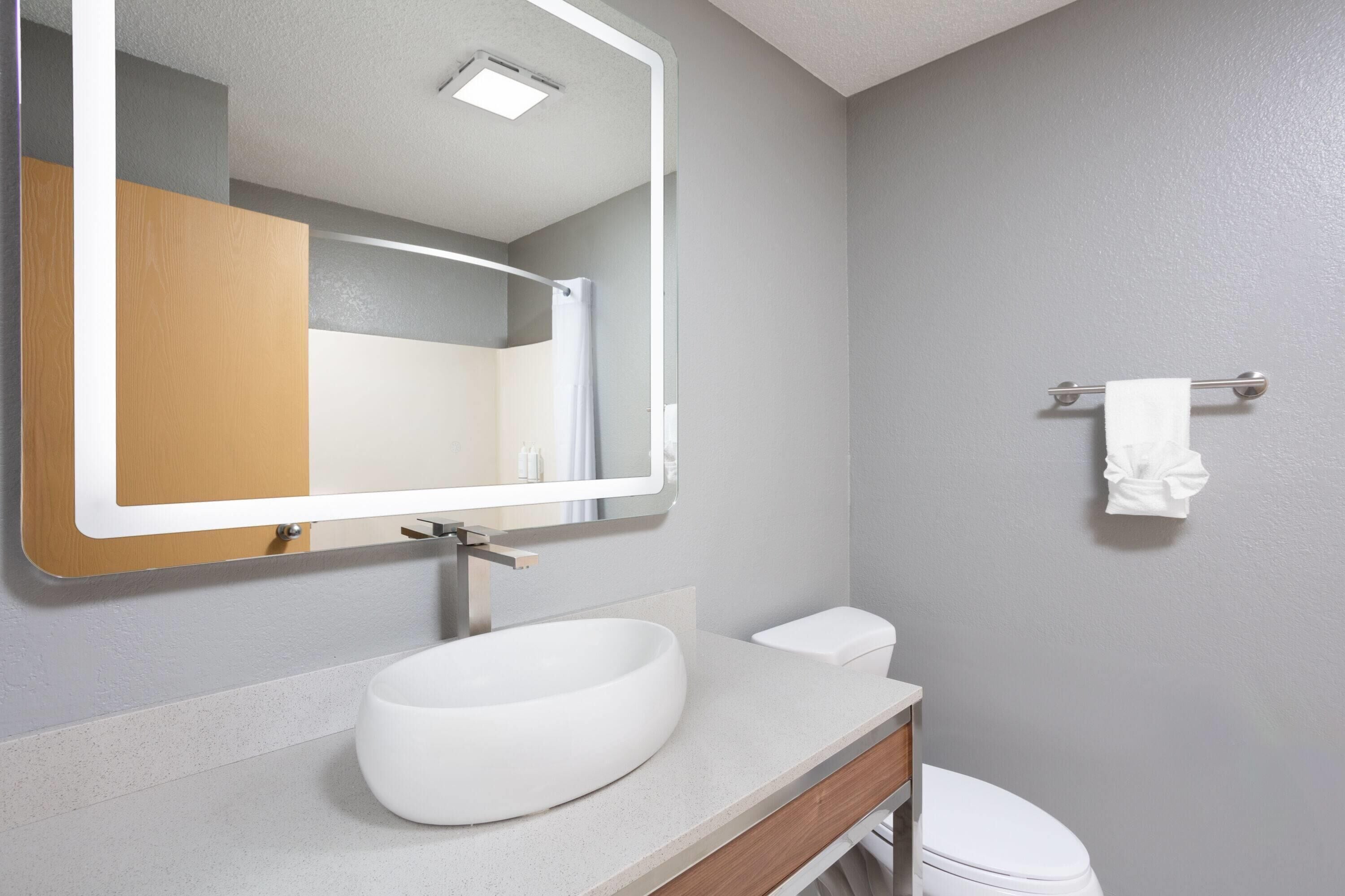 A bathroom with a white sink, a mirror, and a toilet.