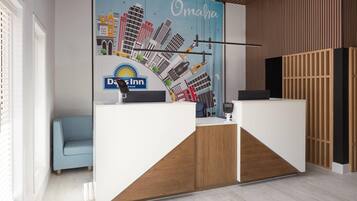 A reception area with a modern design, featuring a white reception desk, a blue sofa, and a cityscape mural on the wall.