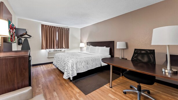 A hotel room with a bed, desk, chair, and two lamps. - Red Roof Inn PLUS+ & Suites Malone (Malone)
