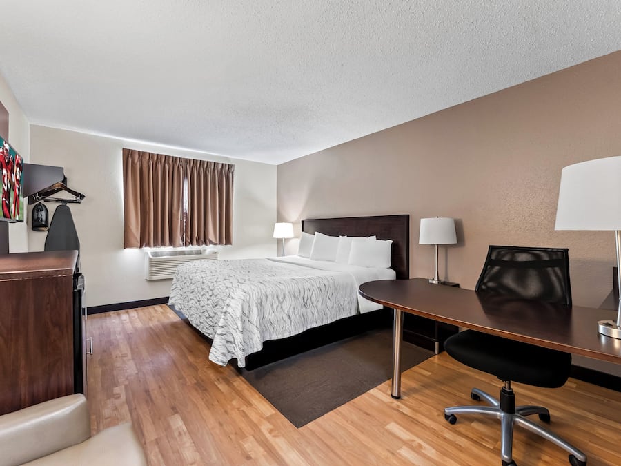 A hotel room with a bed, desk, chair, and two lamps.