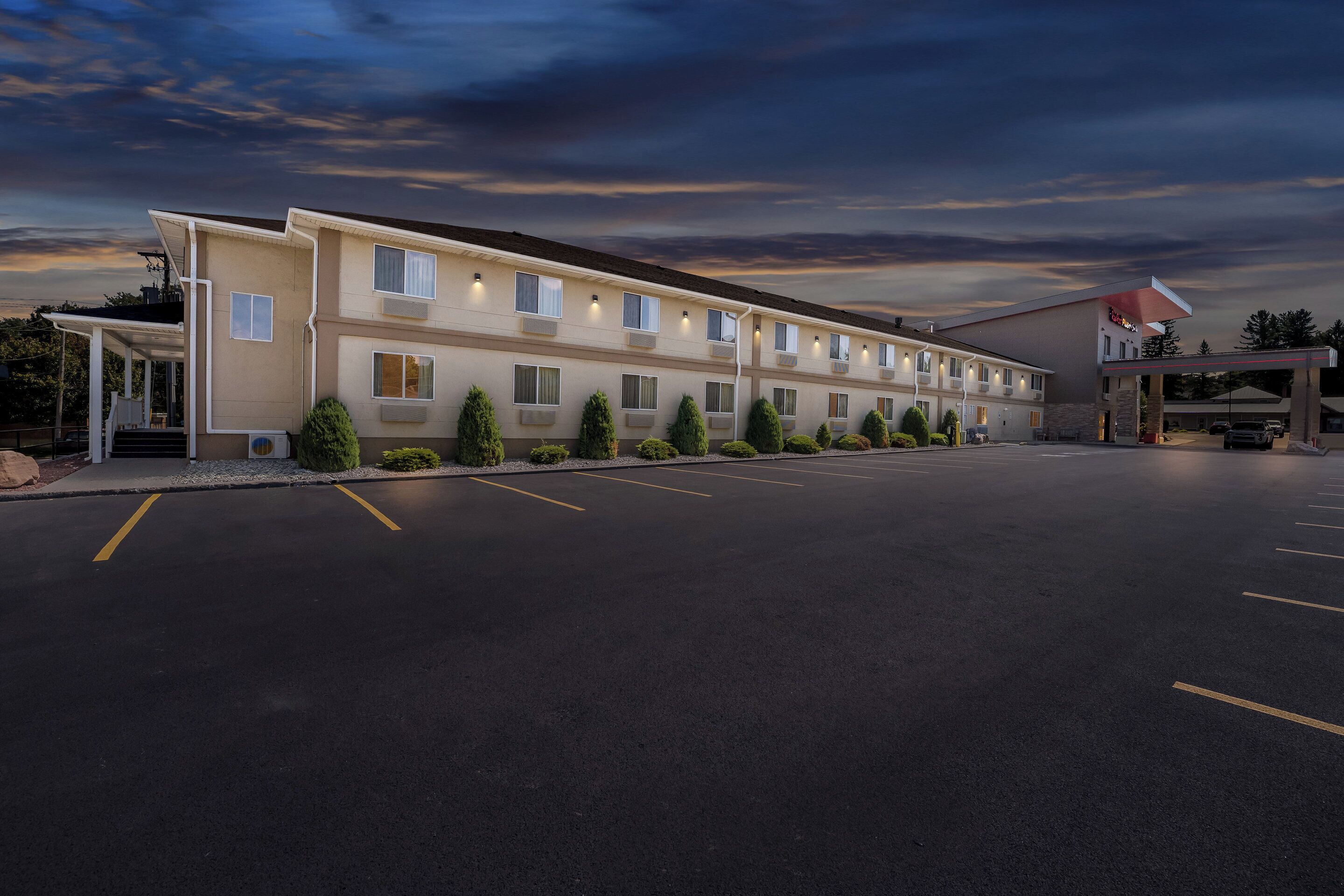 A motel with a row of rooms, a covered parking area, and a gas station.