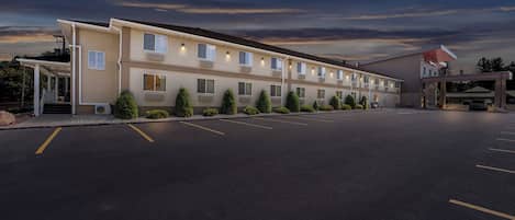 Un motel con una fila de habitaciones, un estacionamiento techado y una gasolinera.