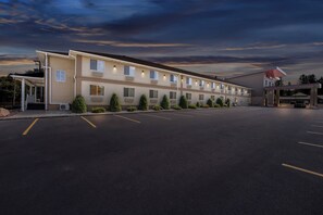 A motel with a row of rooms, a covered parking area, and a gas station. - Red Roof Inn PLUS+ & Suites Malone (Malone)