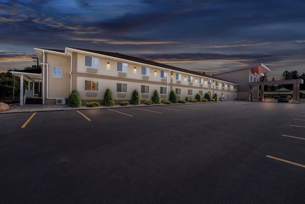 A motel with a row of rooms, a covered parking area, and a gas station.