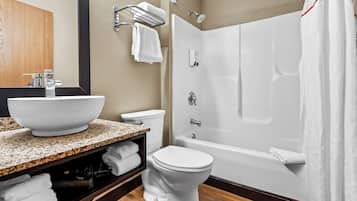 A modern bathroom with a large white sink, a toilet, and a bathtub.