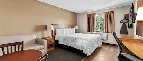 A hotel room with a bed, a sofa, a desk, and a chair.
