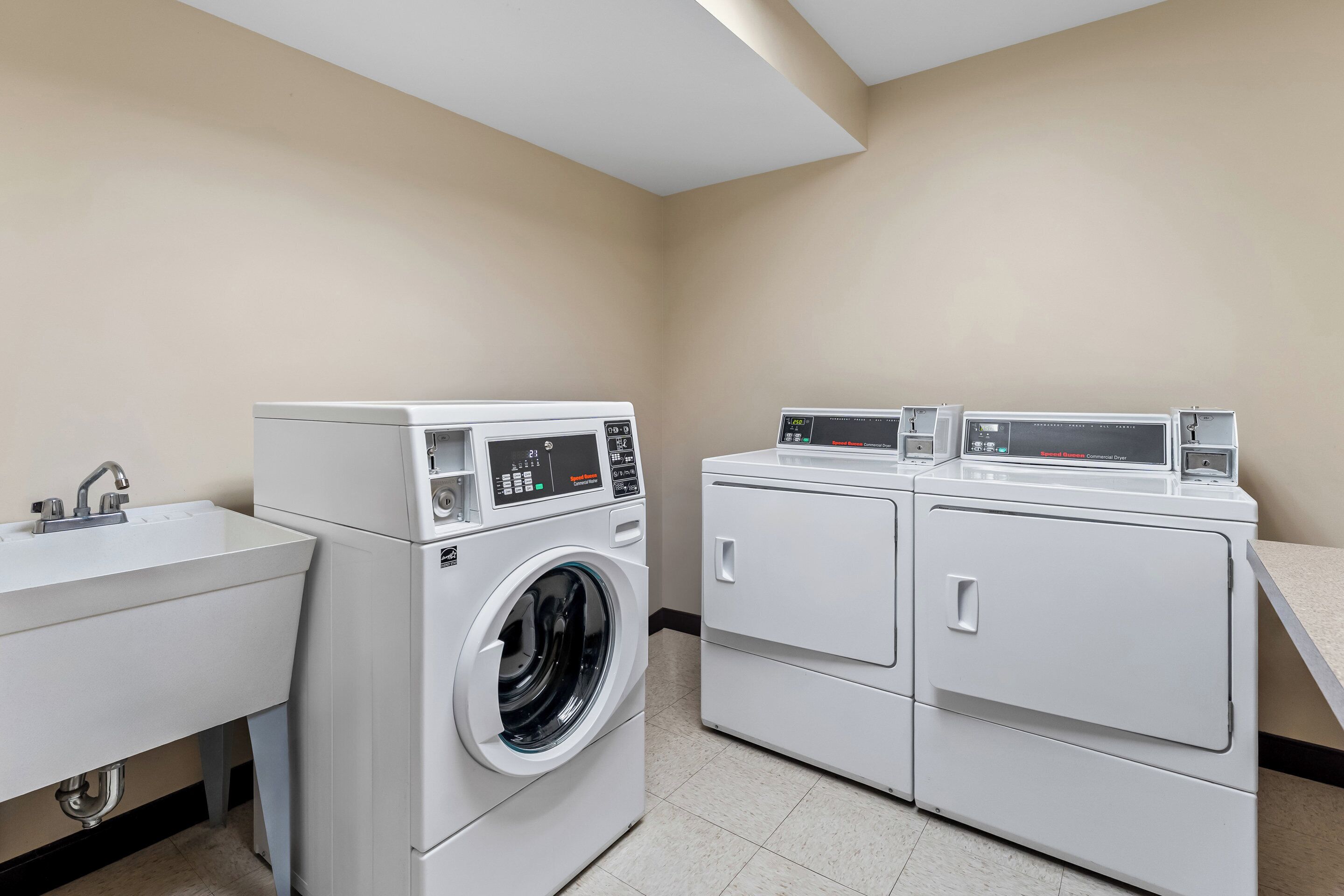Une buanderie équipée d’un lave-linge, d’un sèche-linge et d’un évier.