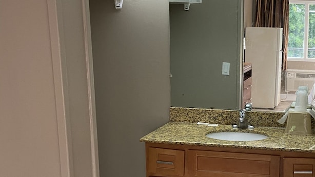 A kitchen with a granite countertop, wooden cabinets, and a built-in oven. - Inn Between The Hedges (Athens)