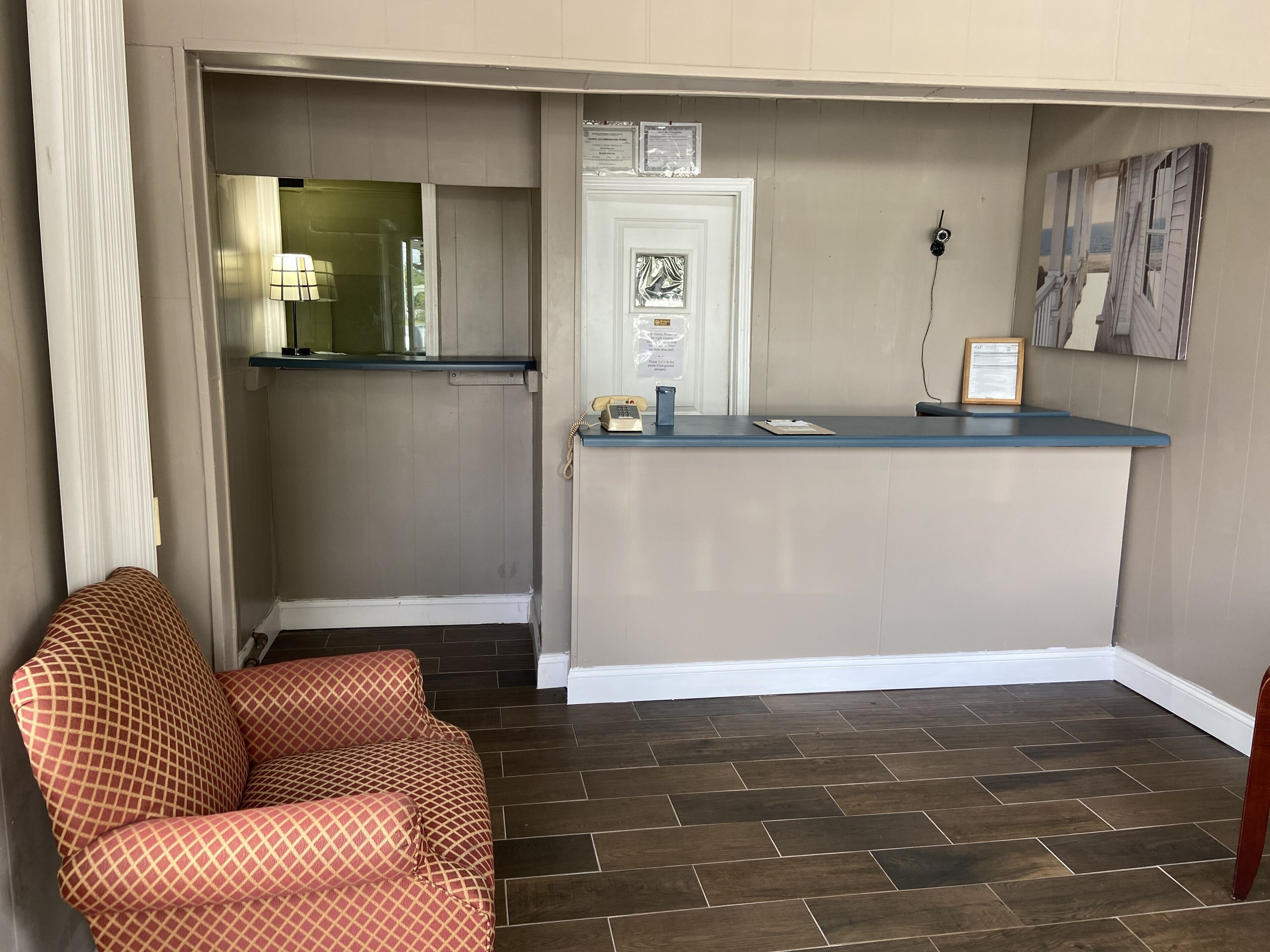 A reception area with a blue counter, a telephone, and a framed notice on the wall.