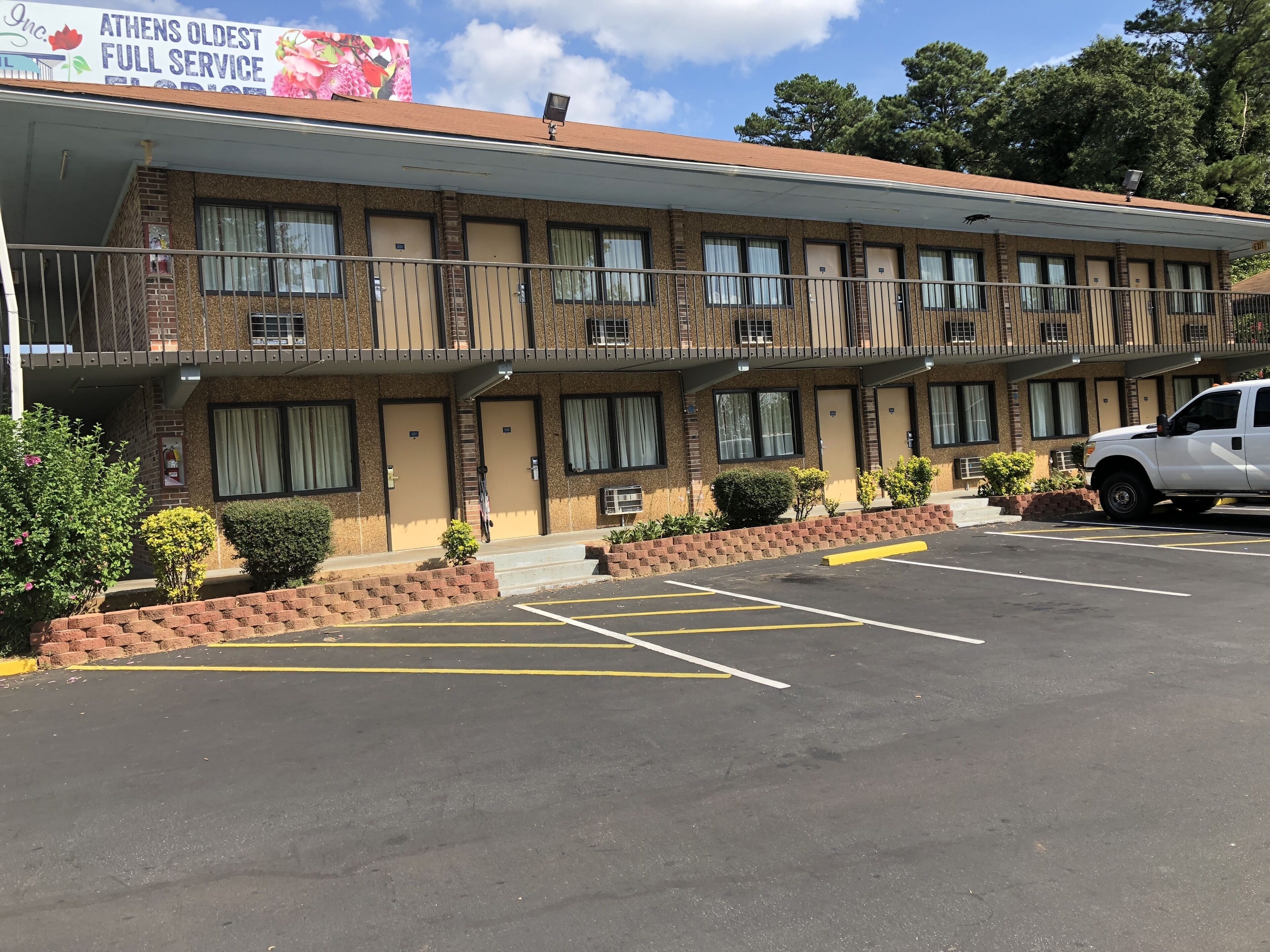 A motel with a brick facade, multiple doors, and a parking lot.