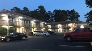A multi-story motel with a parking lot. - Inn Between The Hedges (Athens)