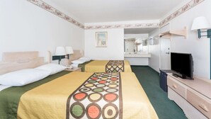 A hotel room with two beds, a television, a desk, and a mirror.