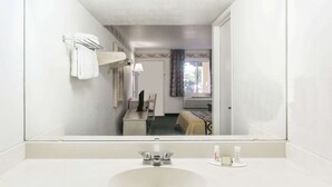 A hotel bathroom with a large mirror, a sink, and a toilet visible in the reflection.