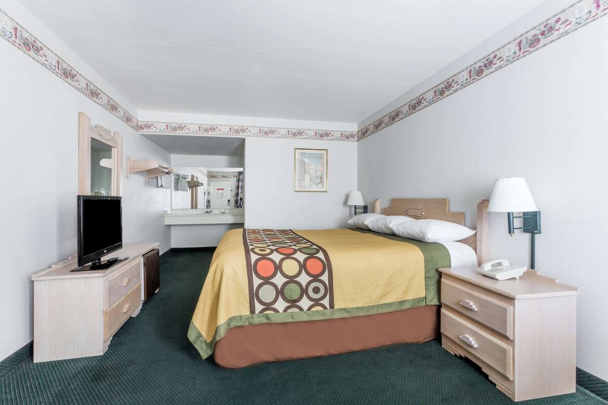 Una habitación de hotel con una cama, un televisor, un escritorio y una lámpara.