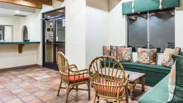 A cozy living area with wicker chairs, a green sofa, and a tiled floor.