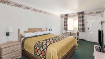 A hotel room with a bed, a desk, a chair, a television, and a wardrobe.