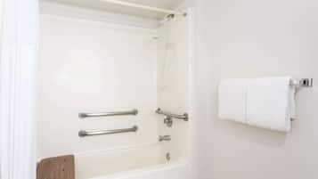 A white bathtub with grab bars, a wooden tray, and a towel rack.