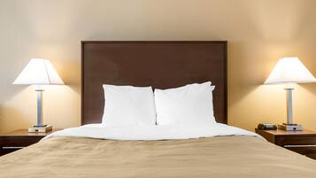 Una habitación de hotel con una cama grande, dos mesitas de noche con lámparas y un cabecero de madera.