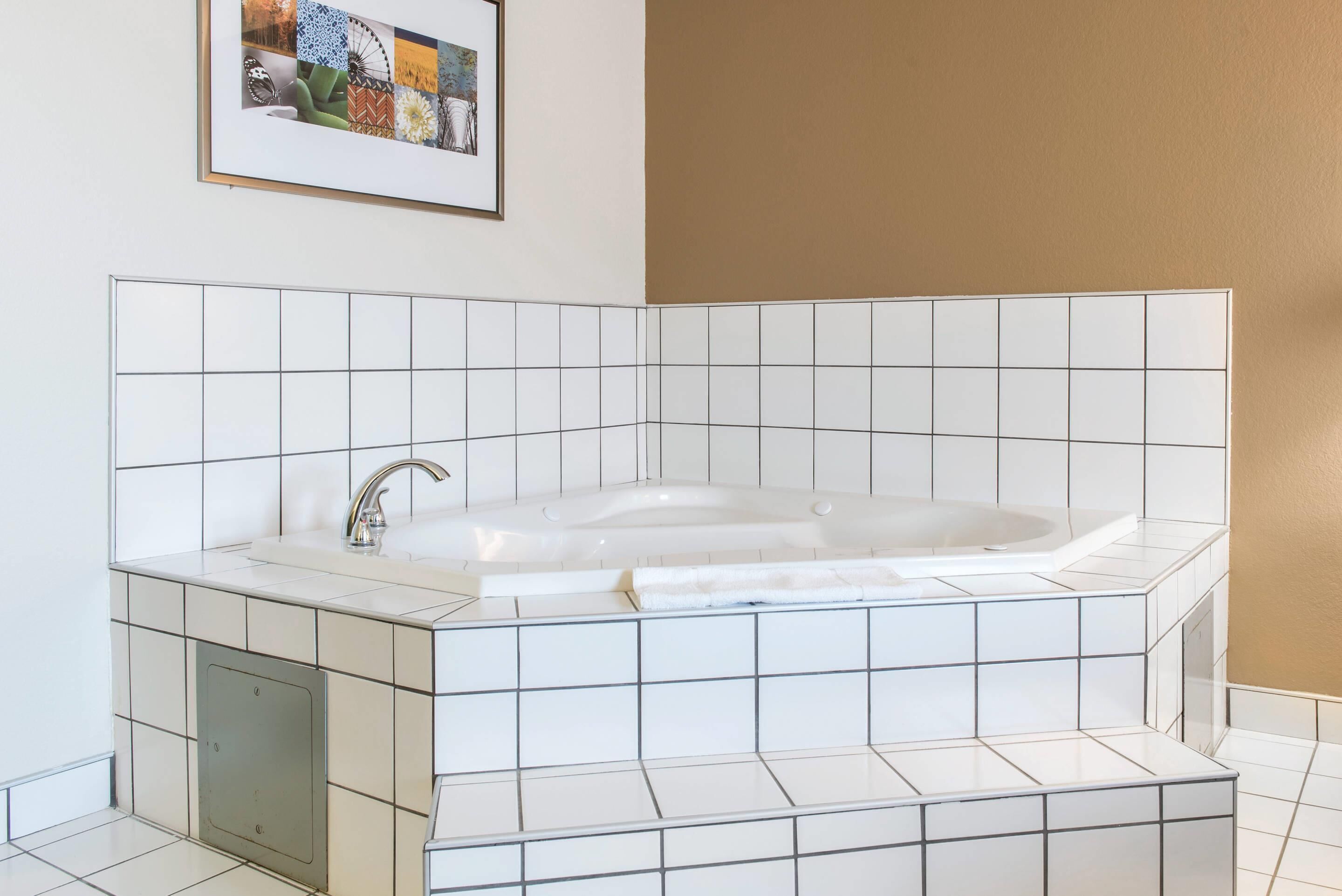Une salle de bain moderne avec une baignoire sur pieds, des carreaux blancs et un tableau encadré au mur.