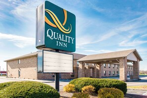 A Quality Inn hotel with a clear sign, a covered parking area, and well-maintained landscaping. - Quality Inn Noblesville - Indianapolis (Noblesville)