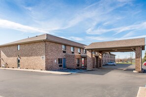 A two-story brick building with a covered parking area and a single-story structure adjacent to it. - Quality Inn Noblesville - Indianapolis (Noblesville)